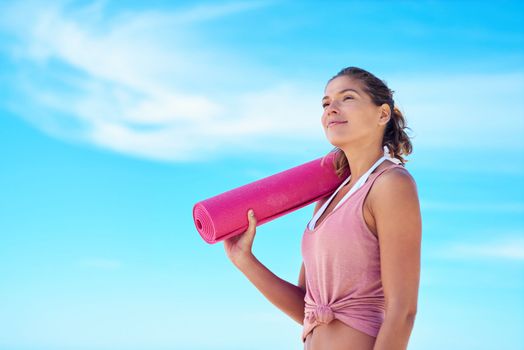 Yoga agrees with nature. a young woman holding a yoga mat while standing outside