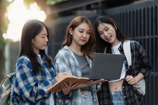 Beautiful young Asian woman college student with friends at outdoors. College student working on the college campus.