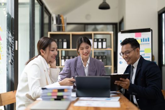 Group of young Asian business people brainstorming, looking at laptop computer.