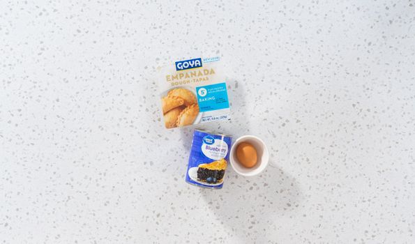 Denver, Colorado, USA-August 15, 2022-Flat lay. Measured ingredients in glass mixing bowls to make sweet empanadas with blueberries.