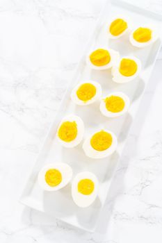 Sliced hard-boiled eggs on a white serving plate.