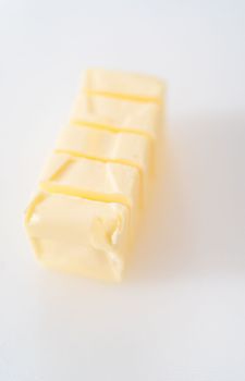Slicing sticks of unsalted butter on a white cutting board.