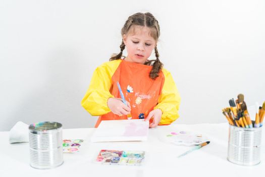 Little girl working on an art project with acrylic paint at homeschool.