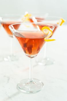 Cosmopolitan cocktail in a martini glass and decorated with a lemon swirl.