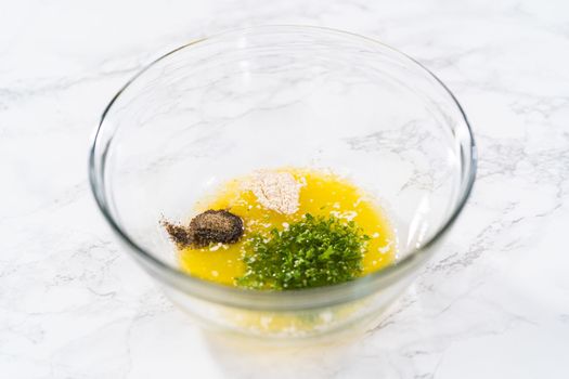 Mixing ingredients in a glass mixing bowl to prepare butter mixture for garlic lobster tails.