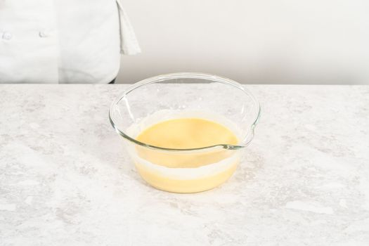 Mixing ingredients in a glass mixing bowl to bake funfettti bundt cake.