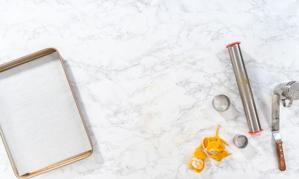 Flat lay. Lemon wedge cookies with lemon glaze. Rolling cookie dough with an adjustable rolling pin and cutting out cookies with cookie cutters to bake lemon wedge cookies with lemon glaze.