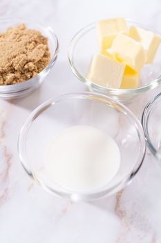 Measured ingredients in a glass mixing bowl to prepare homemade caramel glaze for bundt cake.