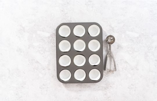 Flat lay. Lining cupcake baking pan with foil cupcake liners to bake unicorn rainbow chocolate cupcakes.