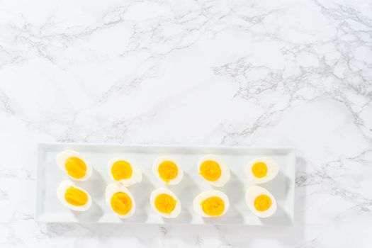 Sliced hard-boiled eggs on a white serving plate.