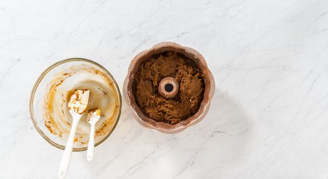 Flat lay. Filling metal bundt cake pan with cake butter to bake gingerbread bundt cake with caramel filling.