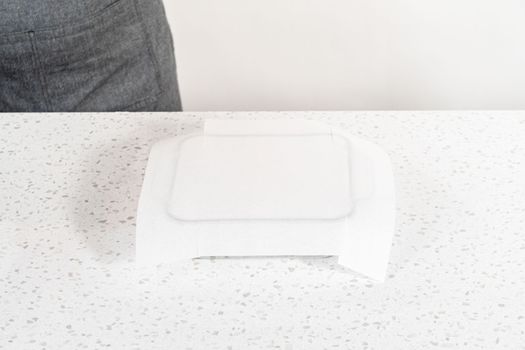 Lining glass baking pan with parchment paper sheet to prepare white chocolate cranberry pecan fudge.