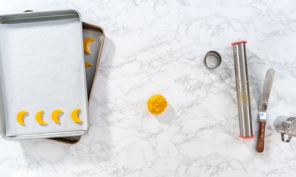 Flat lay. Lemon wedge cookies with lemon glaze. Rolling cookie dough with an adjustable rolling pin and cutting out cookies with cookie cutters to bake lemon wedge cookies with lemon glaze.