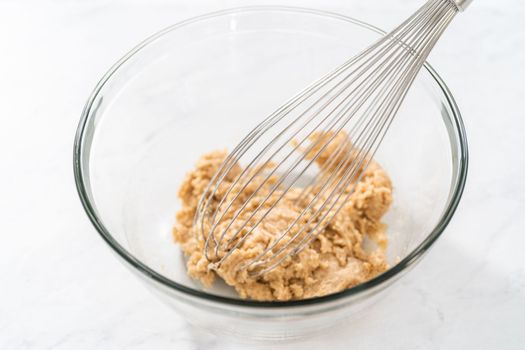 Mixing wet ingredients in a small glass mixing bowl to bake gingerbread bundt cake with caramel filling