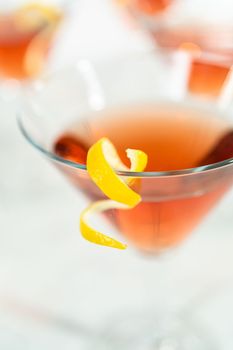 Cosmopolitan cocktail in a martini glass and decorated with a lemon swirl.