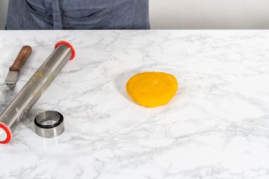 Lemon wedge cookies with lemon glaze. Rolling cookie dough with an adjustable rolling pin and cutting out cookies with cookie cutters to bake lemon wedge cookies with lemon glaze.