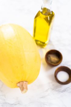 Preparing organic spaghetti squash with olive oil, salt, and pepper.