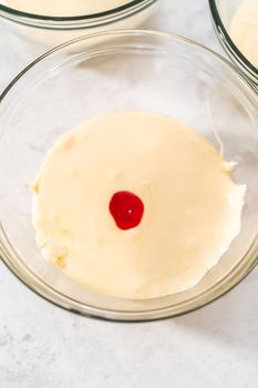 Mixing in orange and yellow food coloring into melted chocolate to prepare candy corn fudge.