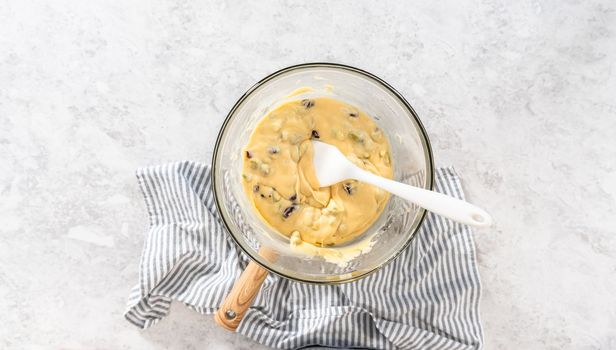 Flat lay. Melting white chocolate chips and other ingredients in a glass mixing bowl over boiling water to prepare cranberry pistachio fudge.