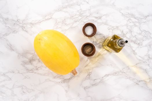 Preparing organic spaghetti squash with olive oil, salt, and pepper.