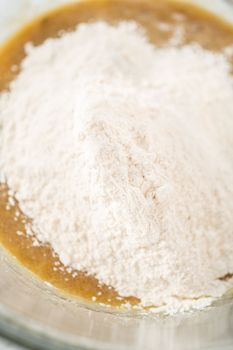 Mixing ingredients in a large glass mixing bowl to bake banana oatmeal muffins.