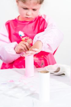 Little girl making a unicorn out of the toilet paper roll and craft paper.
