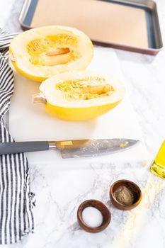 Preparing organic spaghetti squash with olive oil, salt, and pepper.