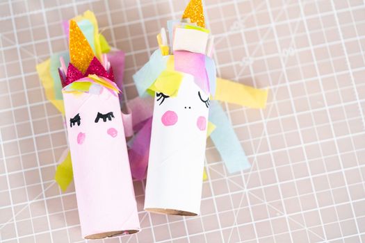 Making a unicorn out of the toilet paper roll and craft paper.