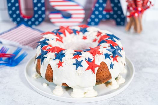 July 4th bundt cake covered with a vanilla glaze and decorated with chocolate stars on a white plate.