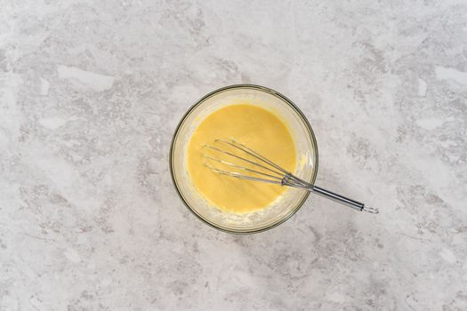 Flat lay. Mixing ingredients in a glass mixing bowl to bake funfettti bundt cake.