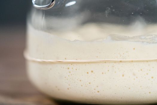 Feeding sourdough starter in a glass mason jar for baking artisan bread.