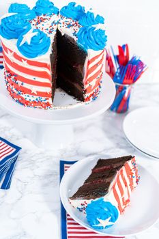 Slicing July 4th chocolate cake decorated with red, white, and blue buttercream frosting.