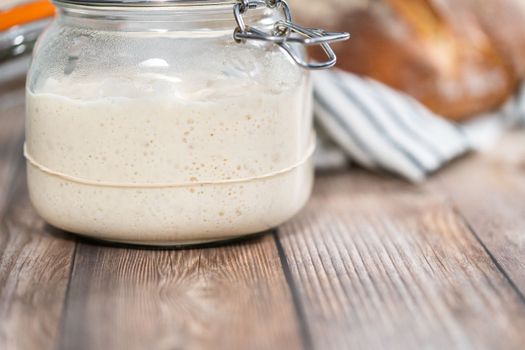 Feeding sourdough starter in a glass mason jar for baking artisan bread.