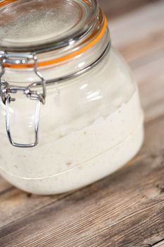 Feeding sourdough starter in a glass mason jar for baking artisan bread.