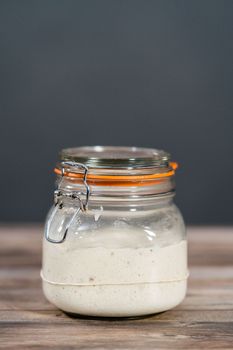 Feeding sourdough starter in a glass mason jar for baking artisan bread.