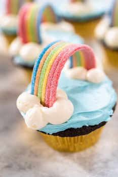 Chocolate cupcakes decorated with blue buttercream frosting and rainbow for unicorn theme birthday party.