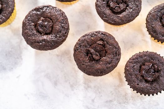 Filling in chocolate cupcakes with chocolate ganache.