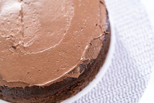 Covering chocolate cake with a crumb layer of chocolate buttercream frosting.