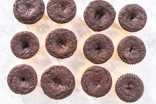 Cooling freshly baked chocolate cupcakes to be decorated with buttercream frosting.