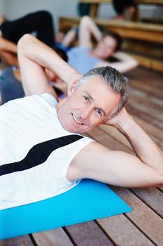 He loves his exercise. A group of people in a gym class doing stomach crunches