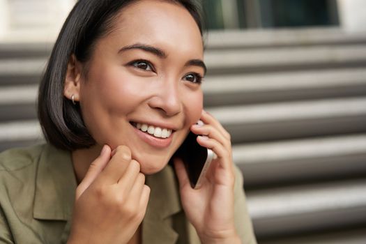 Close up portrait of asian girl talks on mobile phone. Young woman having a phone call, using her telephone.