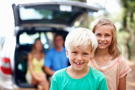 Young boy smiling. Portrait of young siblings smiling with parents sitting in the back of a car