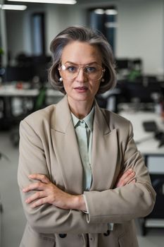 Portrait of an attractive mature caucasian woman with arms crossed on her chest in the office
