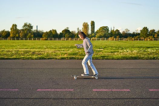 Hobbies and lifestyle. Young woman riding skateboard. Skater girl enjoying cruise on longboard on sunny day outdoors.