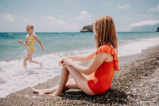 Happy loving family mother and daughter having fun together on the beach. Mum playing with her kid in holiday vacation next to the ocean - Family lifestyle and love concept.