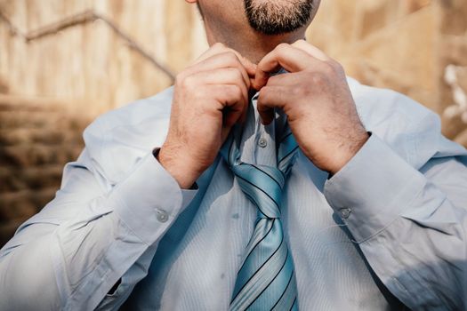 Close up of Man Adjusting Tie of Suit. Businessman in white shirt straightens his tie, close-up.