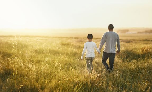 Theres beauty in simplicity. a man taking his son for a walk out on an open field