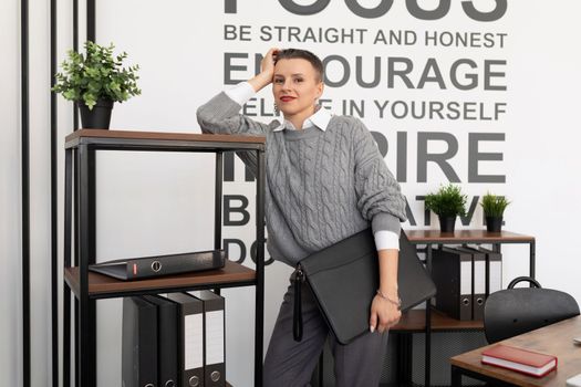 Satisfied businesswoman with a leather folder for documents looking at the camera with a smile in the office.