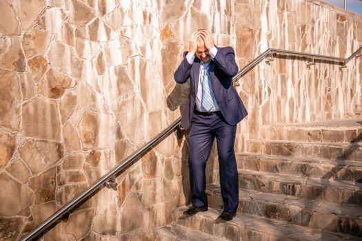 Portrait of a senior professional man in a suit with various problems. A middle-aged businessman with a briefcase descends the stairs.