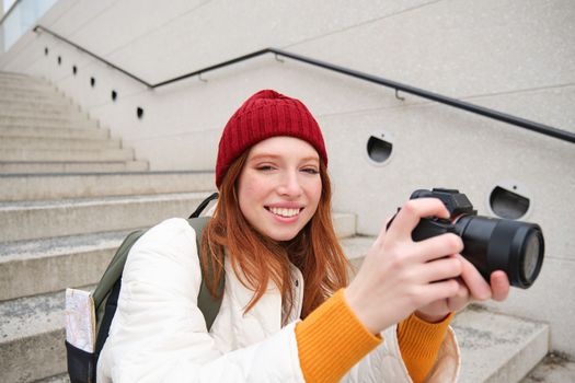 Portrait of female photographer walking around city with professional camera, taking pictures capturing urban shots, photographing outdoors.